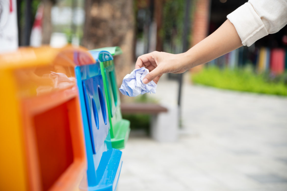 Closeup portrait woman hand throwing crumpled paper in recycling bin. Learning to recycle responsibly and effectively